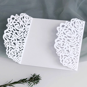 Detail of laser-cut ivory rose floral pattern on elegant tri-fold wedding invitation