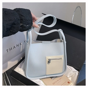 Detail of light blue lychee pattern leather tote bag with stylish cream zipper pocket