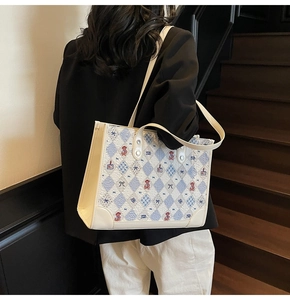 Détail d'un sac cabas beige avec des motifs matelassés bleus et ours brodé mignon
