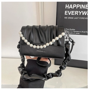 Close-up of black ruched cloud bag featuring a large pearl strap and text detail