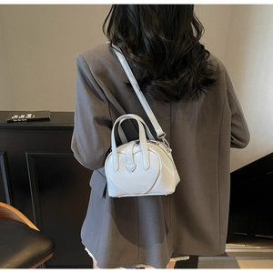 Chic white heart-shaped shoulder bag in glossy patent leather shown on a model