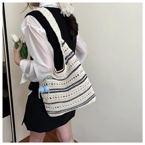 Detail of woven straw tote bag with black and white stripes and blue flower charm