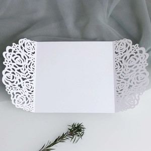 Detail of white laser-cut wedding invitation featuring intricate rose flower hollow patterns