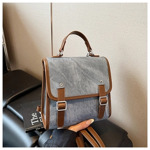 Detail of vintage gray canvas backpack with brown faux leather handles and embossed logo