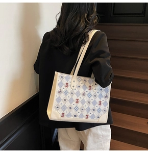 Modèle portant un cabas crème avec motif à carreaux et broderie ours en décor intérieur