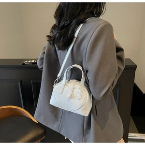 Detail of white leather Boston bag with heart-shaped cutout and silver hardware