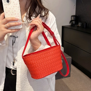 Detail of orange woven bucket bag featuring Intrecciato leather texture and shoulder strap