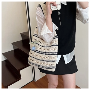 Detail of hollow woven straw tote bag featuring blue stripes and a tulip flower charm