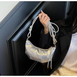 Detail of silver metallic crescent bag with pleated texture and decorative knot strap