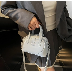 Close-up of a light blue patent leather Boston bag featuring a heart detail and strap