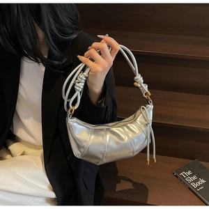 Detail of silver metallic hobo bag with pleated texture and knot strap on a model