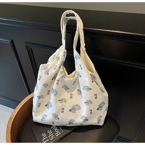 Detail of white canvas tote bag with blue koi fish pattern and textured fabric on black chair