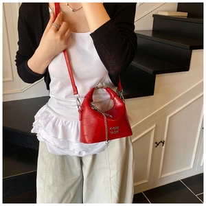 Detail of red crocodile texture crossbody bag with silver chain and metal letter logo