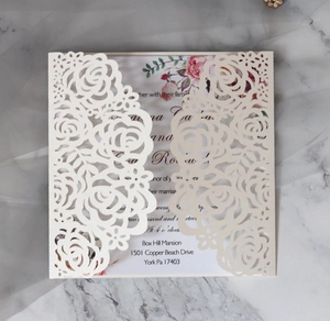 Macro detail of laser-cut rose hollow invitation card on marble background texture