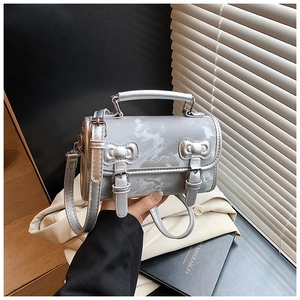 Close-up of silver marble textured handbag featuring dual bow metallic buckles and top handle