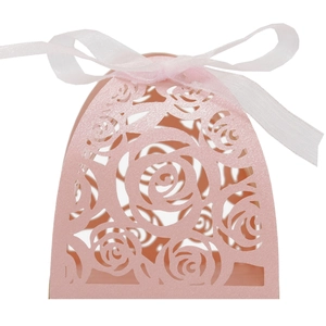 Close-up of pink laser-cut rose hollow candy box with white ribbon for wedding favors