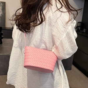 Detail of pink woven leather crossbody bag showing intricate texture and slim shoulder strap