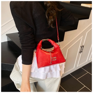 Detail of red faux crocodile leather texture and silver chain on a stylish handbag