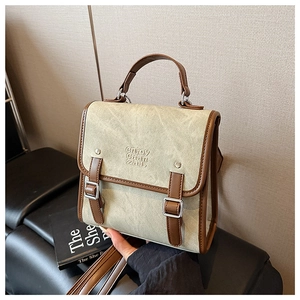 Detail of vintage canvas backpack with contrast leather trim and dual buckle flap closure