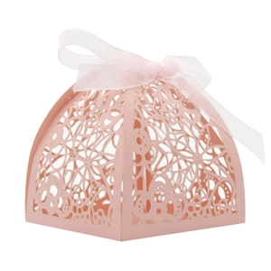 Detail of pink laser-cut wedding favor box featuring floral lace and white ribbon bow