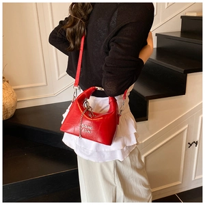 Detail of red crocodile pattern handbag with silver chain and COIH 2DN decorative text