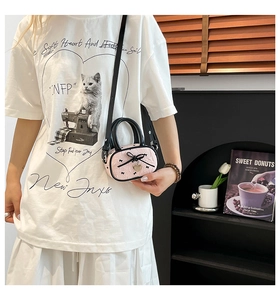 Dettaglio della mini borsa rosa goffrata con fiocco nero e ciondolo a cuore in metallo