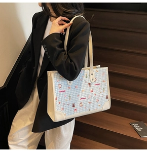 Détail du cabas en tweed bleu clair avec imprimés mignons et poignées en cuir