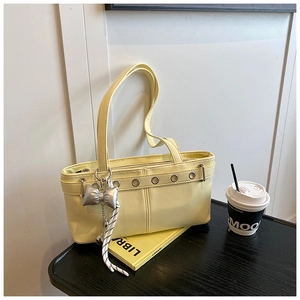 Dettaglio borsa sottospalla gialla con occhielli argentati e ciondolo a fiocco elegante