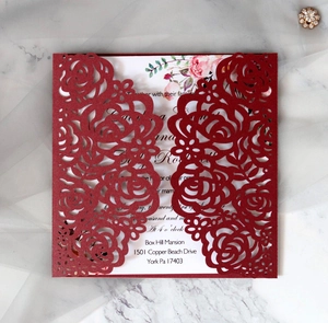 Detailed laser-cut burgundy rose wedding invitation on elegant white marble surface