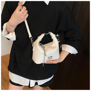 Detailed view of white crocodile pattern leather crossbody bag with silver chain accessory