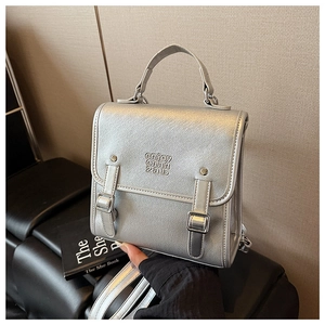 Detail of silver metallic PU briefcase with dual decorative buckle straps and top handle