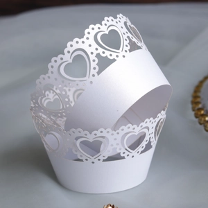 Macro detail of laser-cut heart and lace patterns on white paper cupcake wrappers