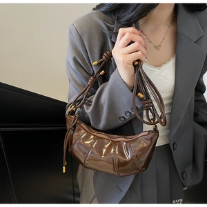 Close-up of brown pleated dumpling bag showing knotted strap and gold metal details