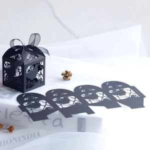 Black laser-cut Halloween favor boxes with ghost patterns and elegant silk ribbons