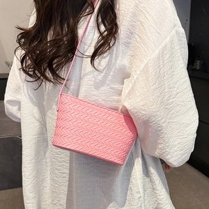 Detail of pink woven leather crossbody bag with minimalist shoulder strap on model