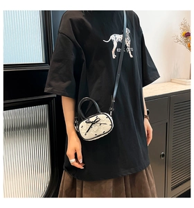 Dettaglio della mini borsa bianca con fiocchi neri e ciondolo a cuore indossata dal modello