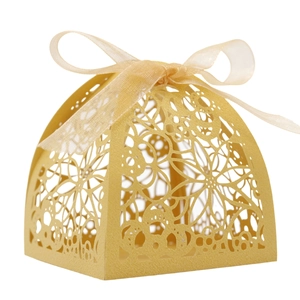 Detailed laser-cut champagne gold favor box with floral patterns and matching ribbon