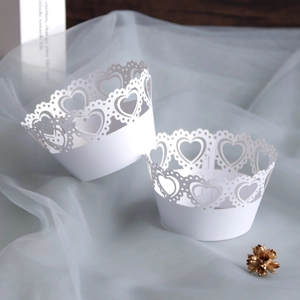 Detail of white laser-cut cupcake wrappers with heart patterns and lace edges