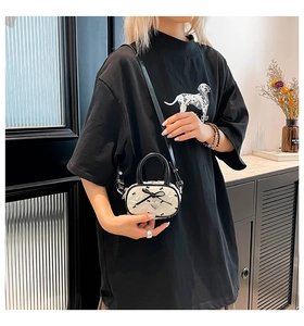 Dettaglio della mini borsa in jacquard bianco con fiocchi neri e ciondolo a cuore