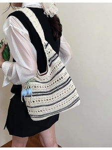 Large woven crochet shoulder bag with black stripes and blue tulip charm accessory