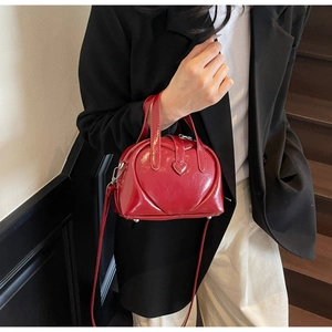 Close-up of a red 3D heart-shaped patent leather handbag with a sleek top handle