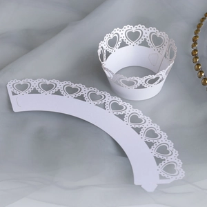 Detail of white laser-cut cupcake wrappers with heart lace patterns for party decor