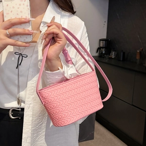Detail shot of the pink woven leather texture and crossbody strap on a small handbag