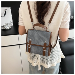 Detailed view of gray vintage canvas backpack with brown leather accents on a model