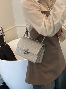Sac bandoulière argenté matelassé avec fermoir nœud porté par un mannequin