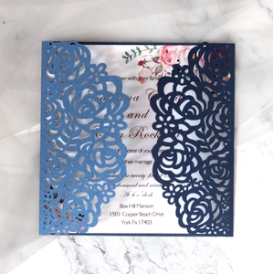 Macro detail of laser-cut floral wedding invitation with navy blue sleeve and rose design