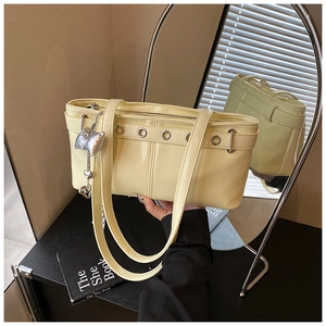 Dettaglio della borsa tote giallo crema con occhielli metallici e ciondolo a fiocco