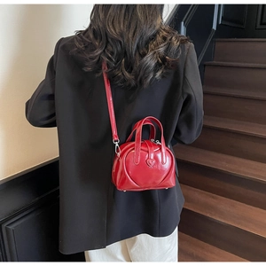 Detail of red heart-shaped patent leather mini bag with double handles and strap
