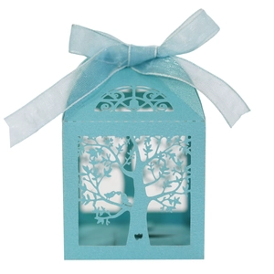 Close-up of light blue laser-cut candy box with intricate tree and bird details and ribbon