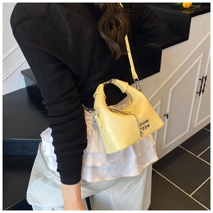 Detail of creamy yellow croc-effect hobo bag with silver chain and metal logo